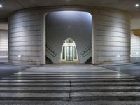 the outside of an empty building at night with a large lit doorway in the middle of the hallway