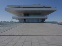 a white building sitting on top of a concrete pier next to a body of water