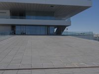 a white building sitting on top of a concrete pier next to a body of water