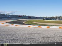 the green road and orange and white stripe line at an event near the racetrack and stadium