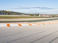 the green road and orange and white stripe line at an event near the racetrack and stadium