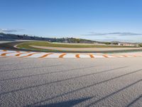 the green road and orange and white stripe line at an event near the racetrack and stadium