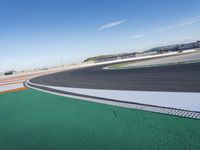 the green road and orange and white stripe line at an event near the racetrack and stadium