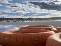 orange rubber hot dogs sit in front of a runway at an airport during the day