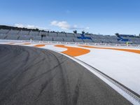 the green road and orange and white stripe line at an event near the racetrack and stadium