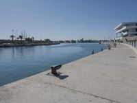 the sidewalk is empty in the foreground of the building and a boat dock at right