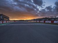 a sun setting over an open racing track during daytime or twilight with a view of a dark sky