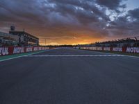 a sun setting over an open racing track during daytime or twilight with a view of a dark sky