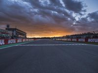 a sun setting over an open racing track during daytime or twilight with a view of a dark sky