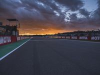 a sun setting over an open racing track during daytime or twilight with a view of a dark sky