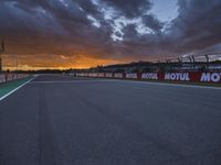 a sun setting over an open racing track during daytime or twilight with a view of a dark sky