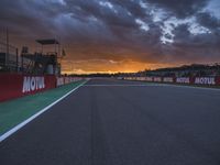 a sun setting over an open racing track during daytime or twilight with a view of a dark sky