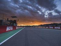 a sun setting over an open racing track during daytime or twilight with a view of a dark sky