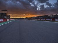 a sun setting over an open racing track during daytime or twilight with a view of a dark sky