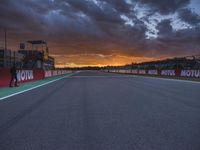 a sun setting over an open racing track during daytime or twilight with a view of a dark sky