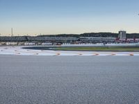 a big wide grey tarmac with a white and orange stripe on it and a plane flying