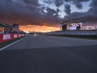 a sun is rising over the racing track during sunset on a cloudy day and is set