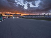 a sun is rising over the racing track during sunset on a cloudy day and is set