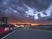 a sun is rising over the racing track during sunset on a cloudy day and is set