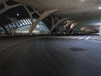 there is a tall structure on a city street at night with cars traveling under it