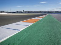 the green road and orange and white stripe line at an event near the racetrack and stadium