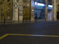 the street is empty during the night with people walking by on the sidewalk and street lights
