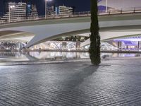 the view of a bridge and its surroundings over a small pool in a city with tall buildings