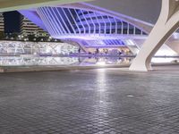 a walkway in a city at night that features many light up displays on the wall