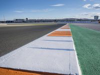 the green road and orange and white stripe line at an event near the racetrack and stadium