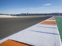 the green road and orange and white stripe line at an event near the racetrack and stadium