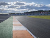 an empty race track in the middle of the day with cloudy skies overhead it is a sunny day