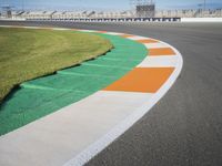 the green road and orange and white stripe line at an event near the racetrack and stadium