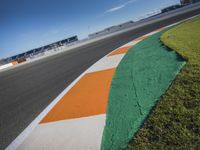 the green road and orange and white stripe line at an event near the racetrack and stadium