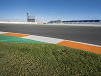 the green road and orange and white stripe line at an event near the racetrack and stadium