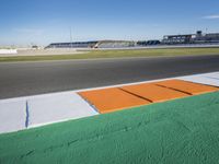 the green road and orange and white stripe line at an event near the racetrack and stadium