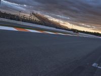 a man racing a race car down a race track at dusk with other people watching