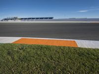 the green road and orange and white stripe line at an event near the racetrack and stadium