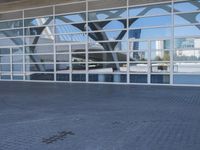 the large building has windows and glass panels in it with the doors open outside the building