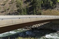 a van crossing over a large road bridge by a mountain stream in the country side