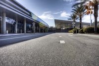 the empty road next to the hotel entrance and palm trees, which is located in a low - angle