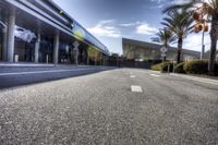 the empty road next to the hotel entrance and palm trees, which is located in a low - angle