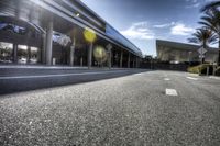 the empty road next to the hotel entrance and palm trees, which is located in a low - angle