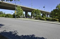 a bike riding across an empty street in a city area with a bridge overhead it