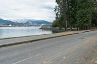 a car drives down the road along a lake that has a pier and a boat in it