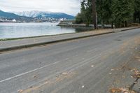 a car drives down the road along a lake that has a pier and a boat in it