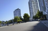 view down a city street at an apartment complex along the water's edge in sunny sun, with cars and buildings in the background
