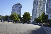 view down a city street at an apartment complex along the water's edge in sunny sun, with cars and buildings in the background