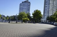 view down a city street at an apartment complex along the water's edge in sunny sun, with cars and buildings in the background