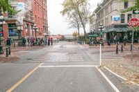 a sidewalk with pedestrians and walking people in it on a rainy day near some tall buildings