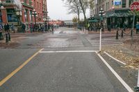 a sidewalk with pedestrians and walking people in it on a rainy day near some tall buildings